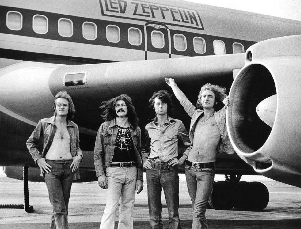 Led Zeppelin rented the Boeing 720 airplane for their 1973 tour. It had two bedrooms (one with an electric fireplace) and a brass bar with a piano built in. This photo represents the excess of the rock lifestyle in the 1970's.
(L-R) John Paul Jones, John Bonham, Jimmy Page and Robert Plant of Led Zeppelin in front of plane in NY. July 24, 1973. © Bob Gruen / www.bobgruen.com