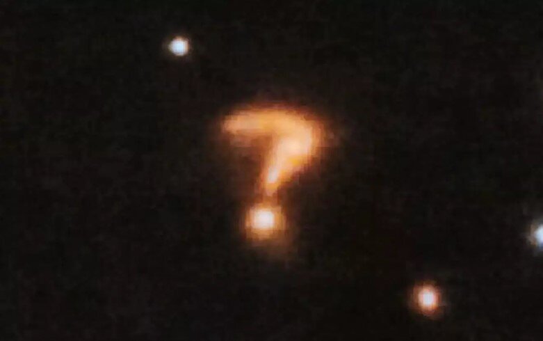 На последних снимках, полученных телескопом Джеймс Уэбб, ученые  обнаружили нечто удивительное - фоновый объект, сильно напоминающий  гигантский вопросительный знак. Но что же это такое?-2