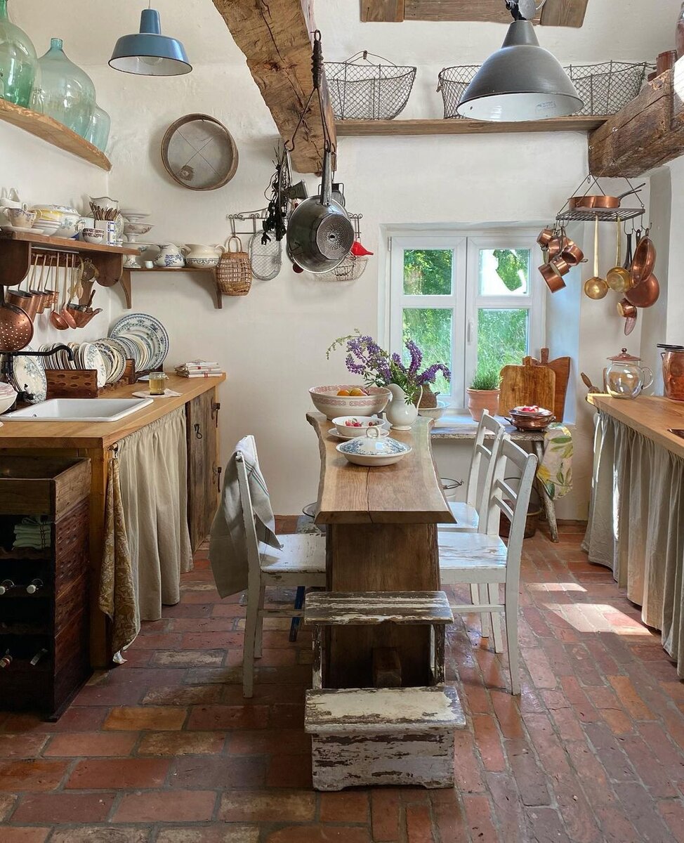Кухня — самое необычное (по-крайней мере для меня) место в этом доме. Интерьер переносит тебя назад на 100-150 лет. Голые кирпичные полы, стол из слэба, занавески на шкафчиках и куча-куча винтажной посуды на видном месте