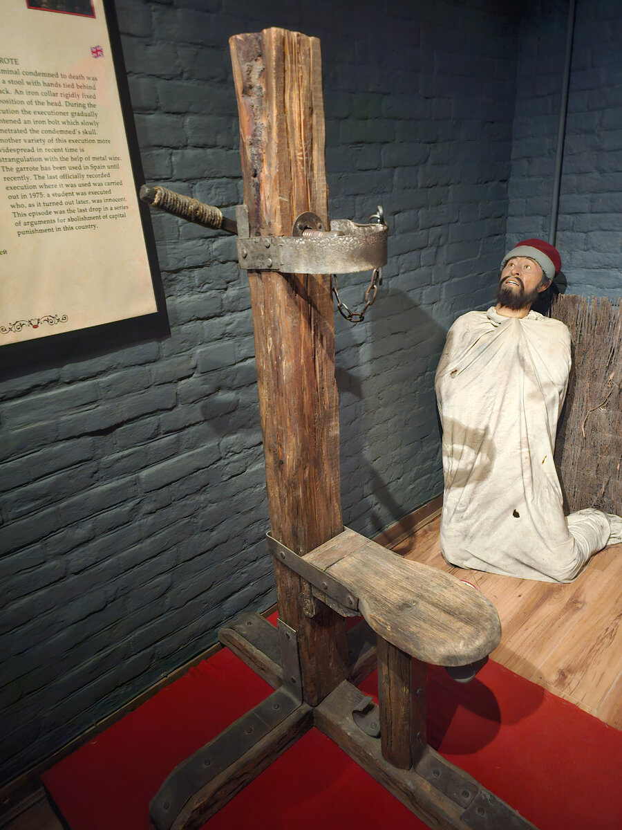 Здесь приковывали руки и ноги. Голову вставляли в отверстие и в неё медленно вкручивали штырь, пока человек не сознается. Справа мешок, в который завязывали человека. В мешке была кислота. 