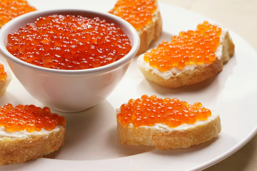 Бутерброд с красной икрой – самое что ни на есть русское блюдо, вкусное, простое, полезное и калорийное. Такие бутерброды являются неизменными спутниками различных праздников и торжеств. Лучшей закуски Вы не найдете и днем с огнем, в ней все сбалансировано – белки, жиры, углеводы и солевой и кислотно-щелочной баланс. Но такие бутерброды можно приготовить не только с красной (лососевой) икрой, если позволяют возможности, то бутерброд с черной (осетровой) икрой будет еще вкуснее, а если возможностей нет, то на масло можно намазать любую другую икру – минтая, икру мойвы или бычков, или даже искусственную белковую икру, все равно получается вкусно.