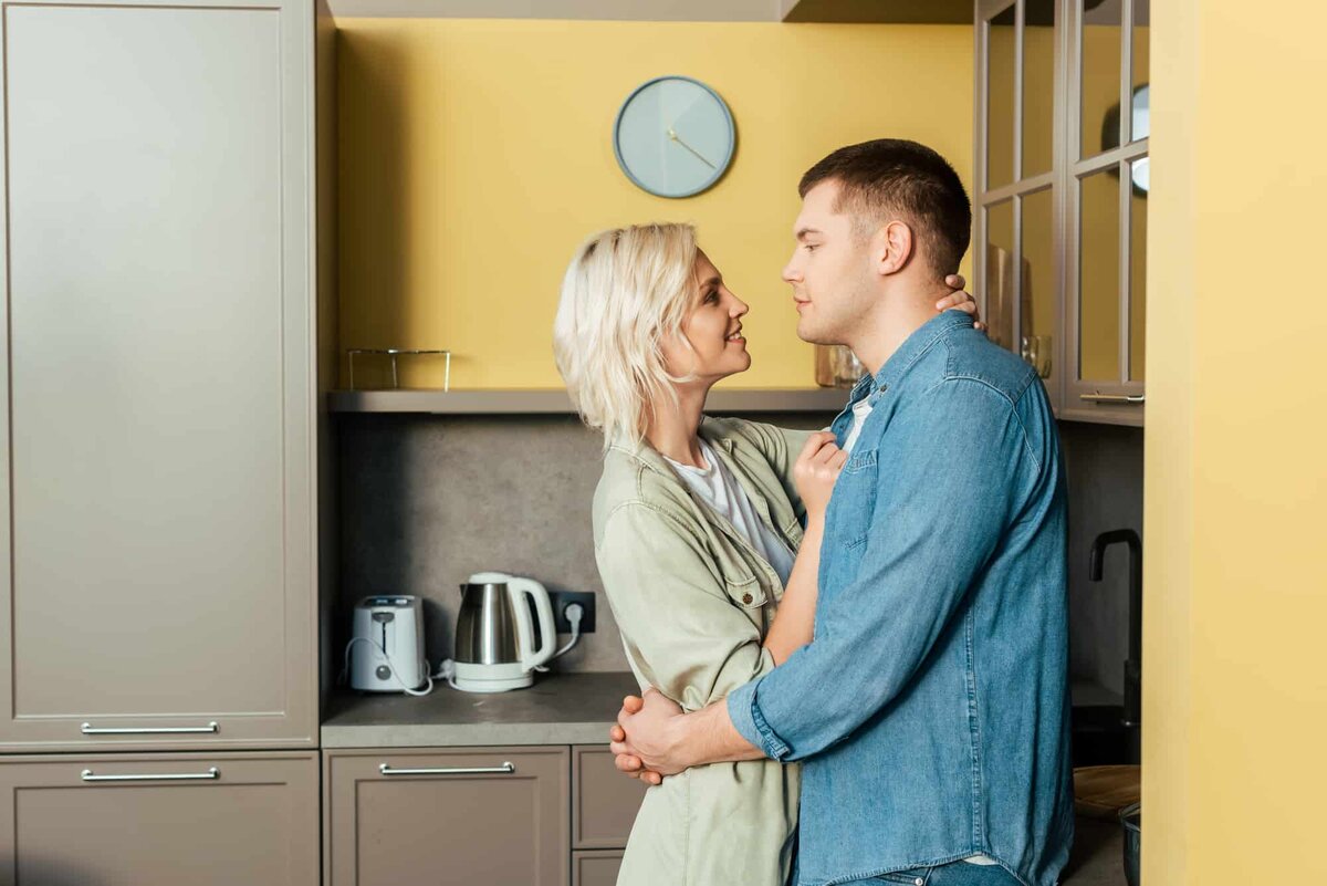 Муж обнимает жену на кухне
