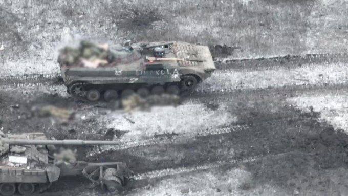Скрин с видео снятого с дрона врага, наш БМП и уничтоженный Т - 80 с тралом, тела погибших и раненых.