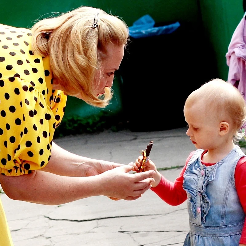 Мама угощает ребенка. Женщина дает ребенку конфету. Дети улицы. Бабушка с ребенком на улице. Мамы без на улице